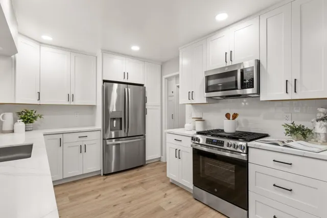 a kitchen with stainless steel appliances white cabinets a stove a microwave and a refrigerator