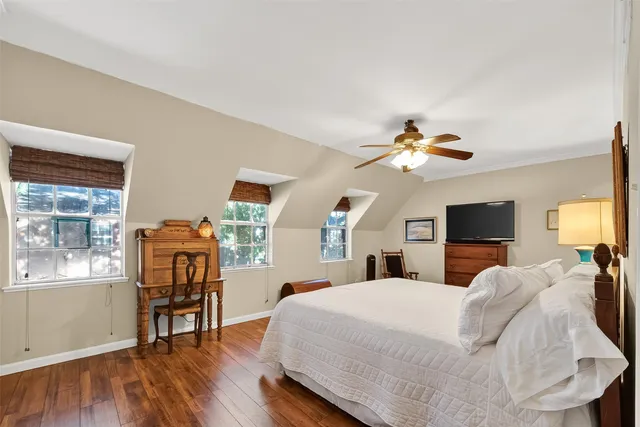 a bedroom with a bed a mirror on dresser and a wooden floor