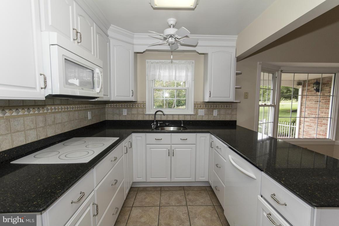 9911 Pepper Hill Road Perry Hall, MD 21128 - Photo 7 of 30 a kitchen with granite countertop white cabinets white appliances a sink and a window