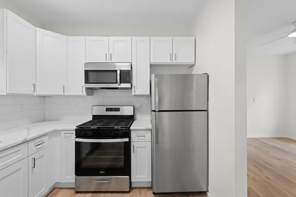 a kitchen with a refrigerator stove and white cabinets