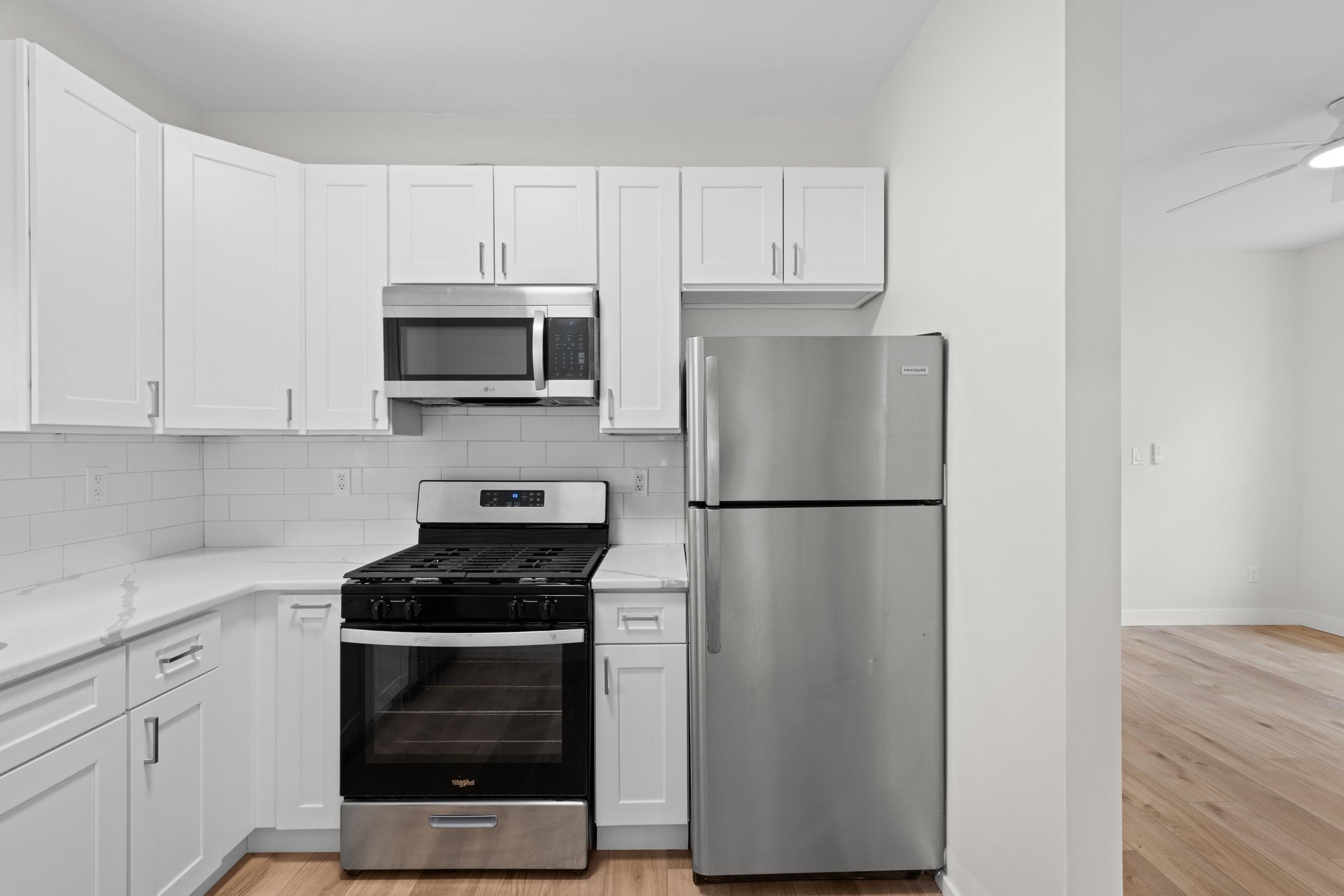 3 Edison Place, Unit 1 East Rutherford, NJ 07073 - Photo 2 of 21 a kitchen with a refrigerator stove and white cabinets