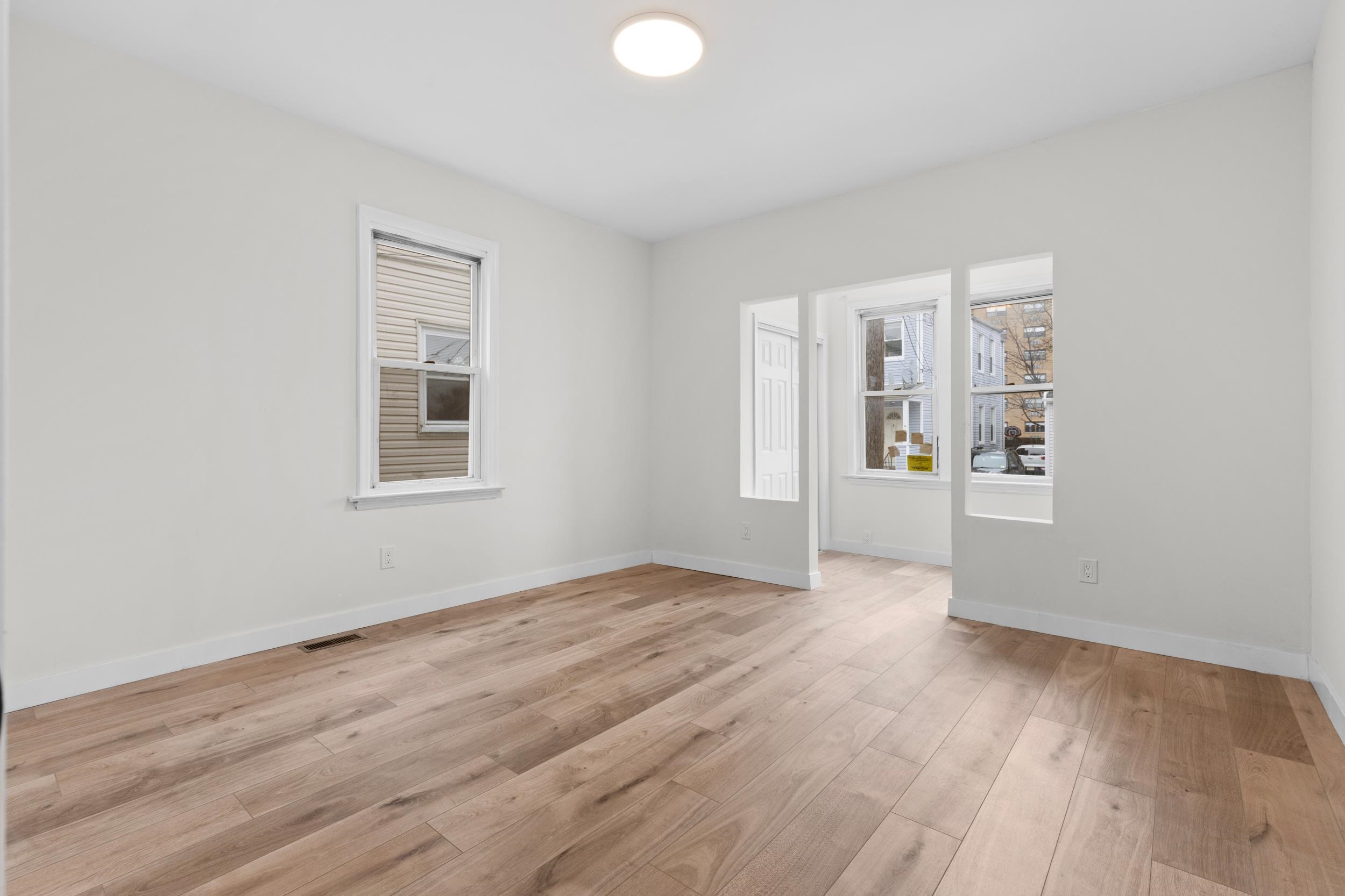 3 Edison Place, Unit 1 East Rutherford, NJ 07073 - Photo 3 of 21 an empty room with wooden floor and windows