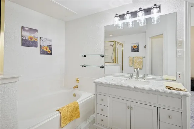 a bathroom with a granite countertop sink a mirror a shower and a bathtub