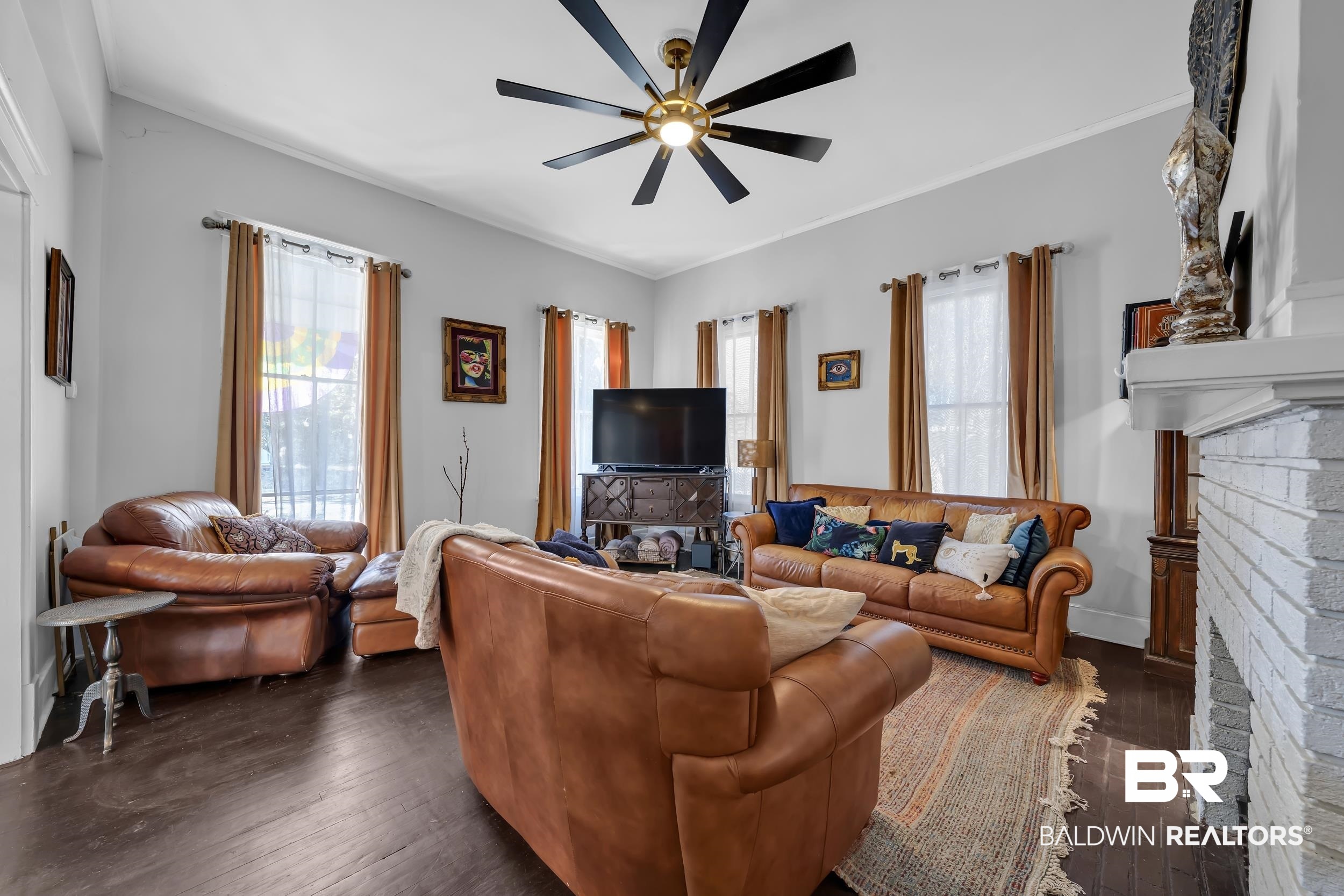 1322 Dauphin Street Mobile, AL 36604 - Photo 6 of 21 Living room featuring dark wood-style flooring, a brick fireplace, ornamental molding, ceiling fan, and plenty of natural light