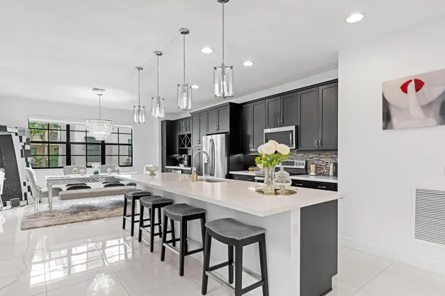 a kitchen with stainless steel appliances granite countertop a stove top oven a sink a dining table and chairs with wooden floor