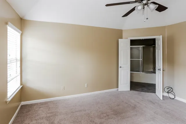 an empty room with a window and a ceiling fan