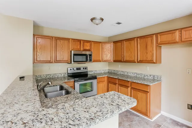 a kitchen with stainless steel appliances granite countertop a sink stove microwave and refrigerator