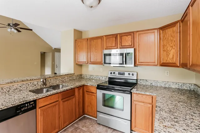 a kitchen with granite countertop a sink stove and cabinets