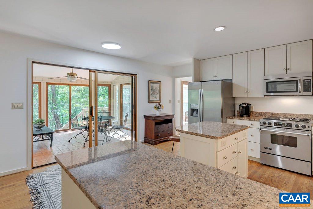 1903 Stillhouse Road Charlottesville, VA 22901 - Photo 12 of 44 a large white kitchen with granite countertop a stove a refrigerator a sink dishwasher a dining table and chairs with wooden floor