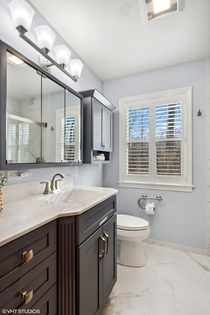 557 Riford Road Glen Ellyn, IL 60137 - Photo 17 of 25 a bathroom with a granite countertop sink a large mirror and a toilet