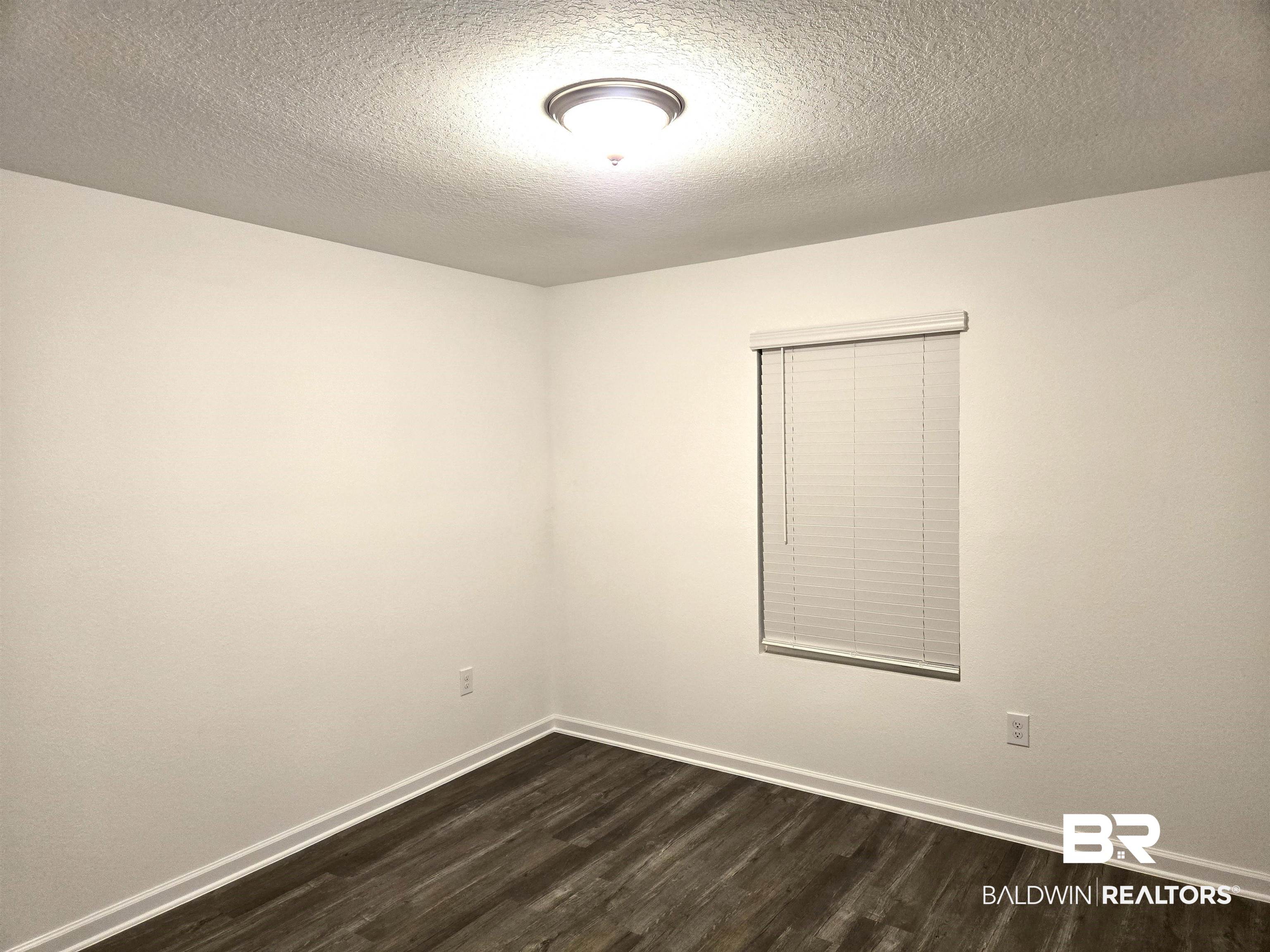 24321 Ringneck Loop Elberta, AL 36530 - Photo 20 of 39 Empty room with dark wood-type flooring and a textured ceiling