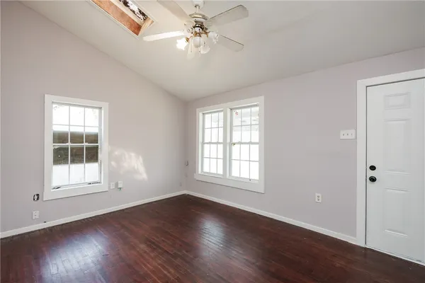 an empty room with wooden floor chandelier fan and windows