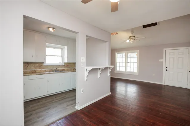 a room with kitchen island granite countertop wooden floors and white cabinets