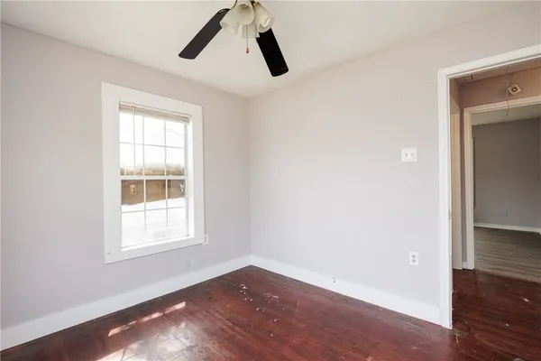 an empty room with wooden floor cabinet and windows