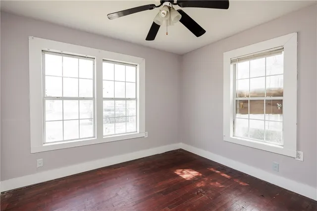 a view of empty room with wooden floor and windows