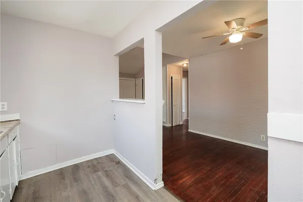 an empty room with wooden floor and fan