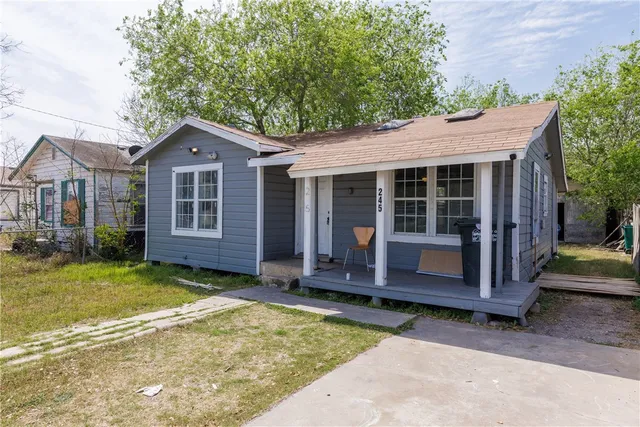 a view of a house with a yard plants and large tree