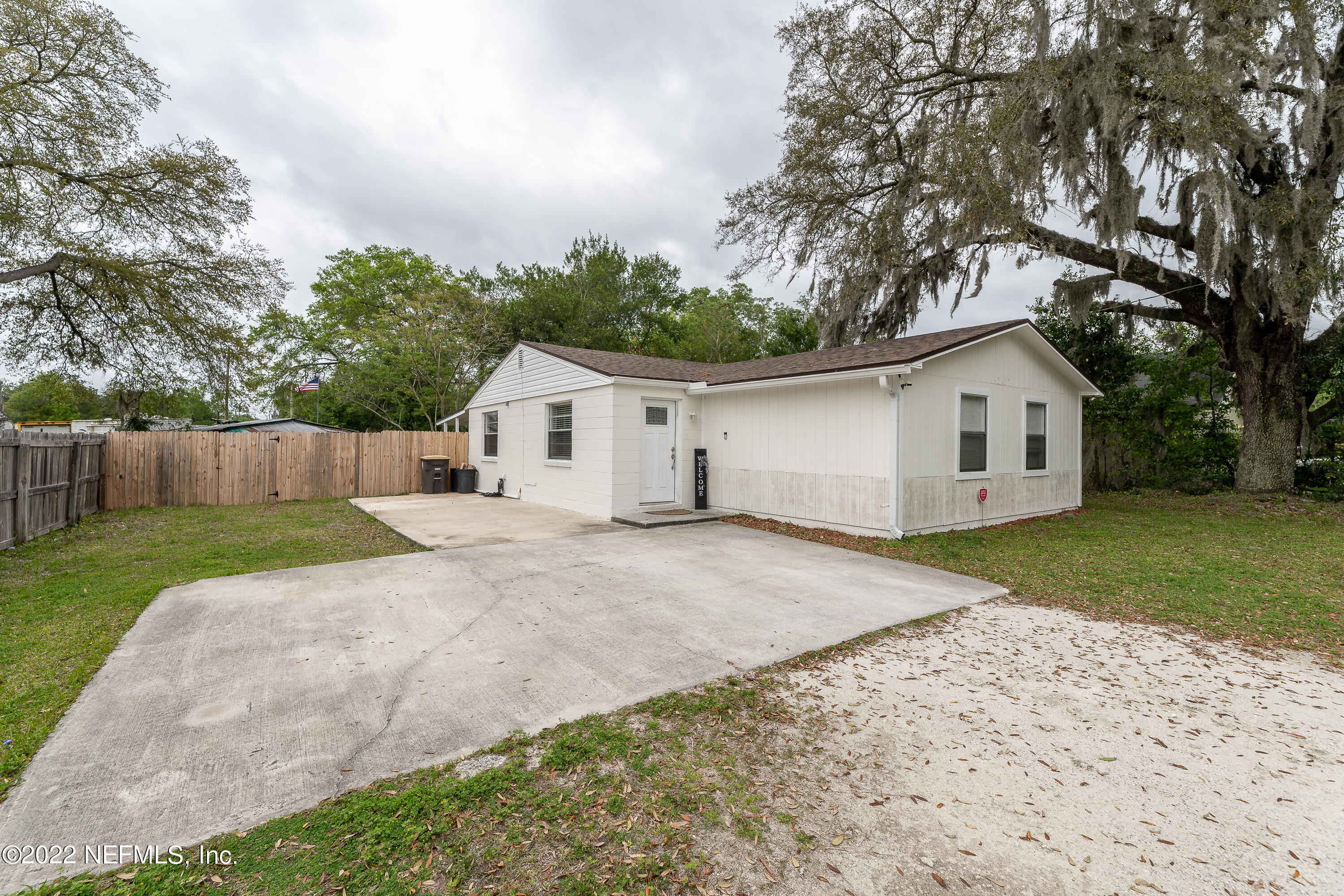 a view of a white house with a yard and large tree