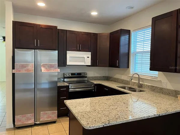a kitchen with granite countertop a refrigerator and a sink