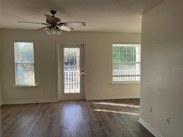 a view of an empty room with a window and wooden floor