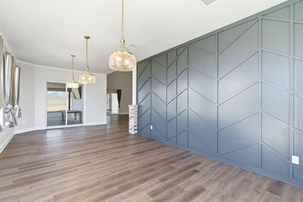 4600 B Old Brock Road Weatherford, TX 76087 - Photo 17 of 40 Unfurnished dining area with an accent wall, wood finished floors, and ornamental molding