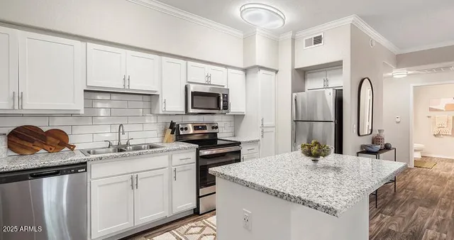 a kitchen with stainless steel appliances granite countertop a sink stove refrigerator and cabinets