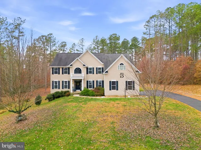 a front view of a house with a yard and large trees