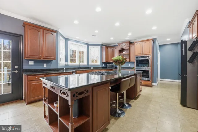 a large kitchen with kitchen island granite countertop a large window and stainless steel appliances