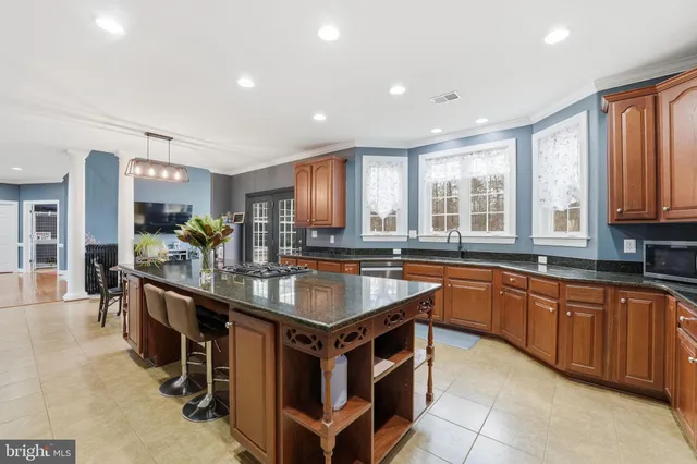 a kitchen with stainless steel appliances granite countertop a refrigerator a sink dishwasher a stove and a dining table with wooden floor