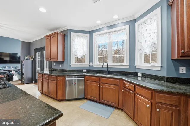a kitchen with stainless steel appliances granite countertop a stove a sink dishwasher and cabinets with wooden floor