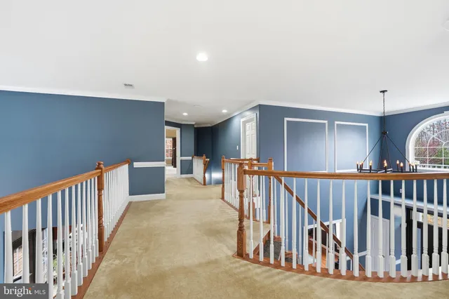 a spacious bedroom with a bed a bookshelf and a chandelier
