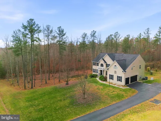 a view of a house with a big yard and large trees