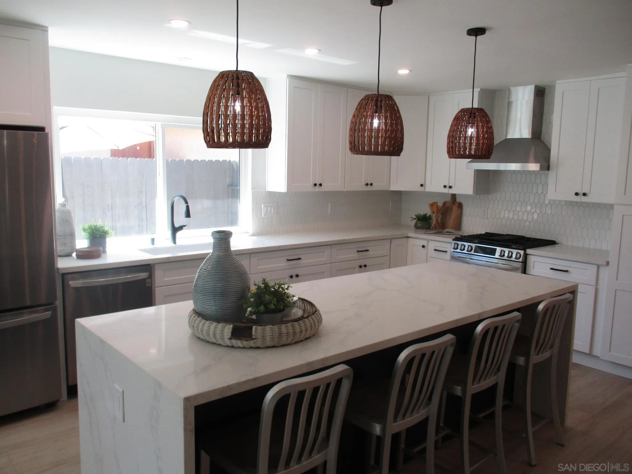 141 Solace Court Encinitas, CA 92024 - Photo 3 of 16 a kitchen with stainless steel appliances granite countertop a stove a sink a dining table and chairs with wooden floor
