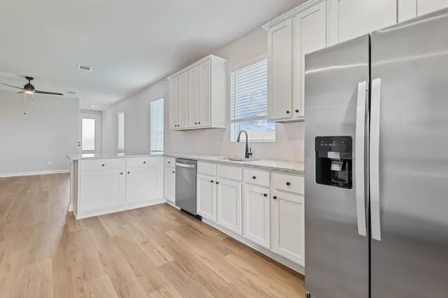 a kitchen with stainless steel appliances granite countertop a refrigerator a stove and a sink
