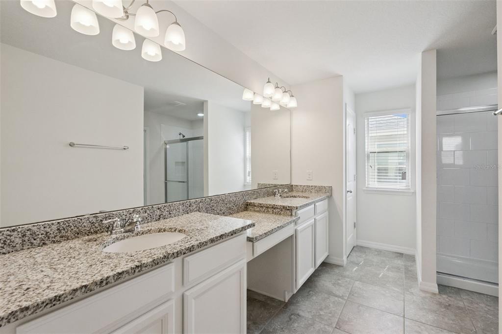 16031 Pebble Blf Loop Winter Garden, FL 34787 - Photo 18 of 51 a bathroom with a granite countertop sink a large mirror and a shower