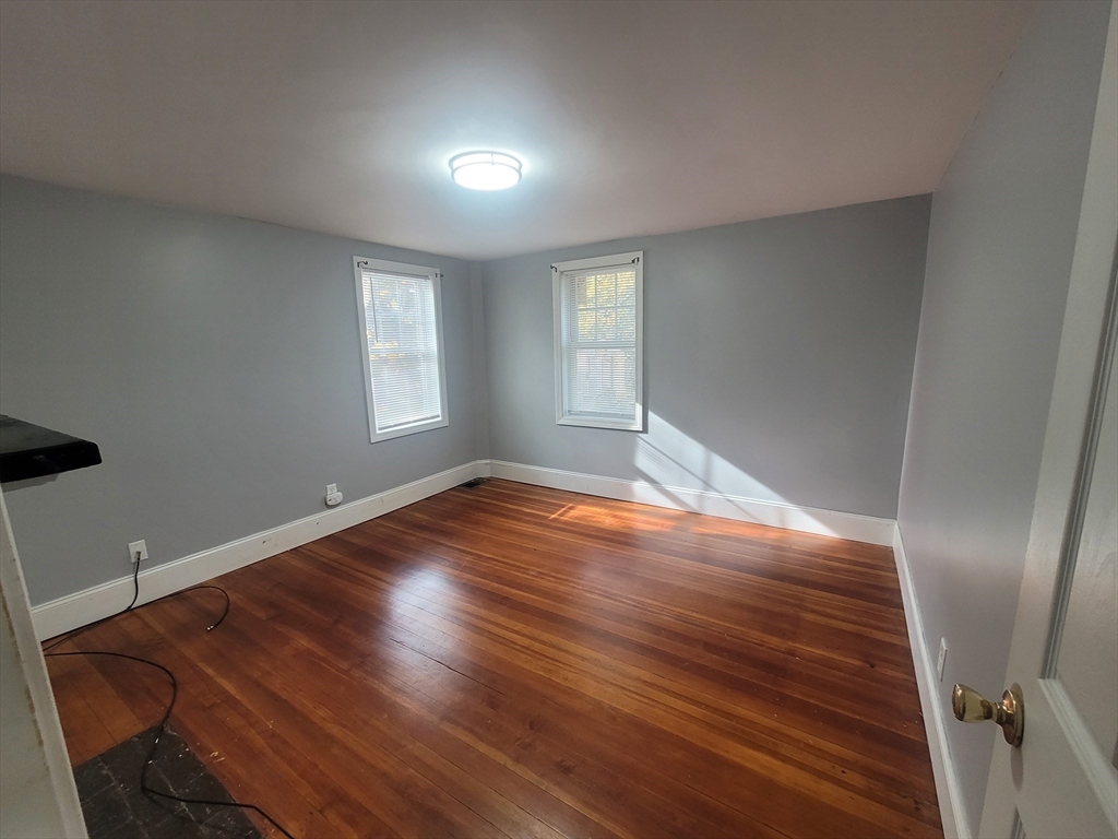 237 Colburn Street, Unit 237 Dedham, MA 02026 - Photo 11 of 16 an empty room with wooden floor and windows