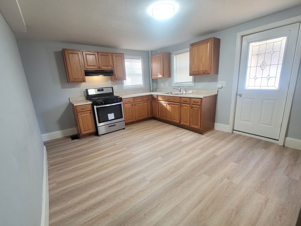 237 Colburn Street, Unit 237 Dedham, MA 02026 - Photo 6 of 16 a kitchen with granite countertop a refrigerator and wooden cabinets