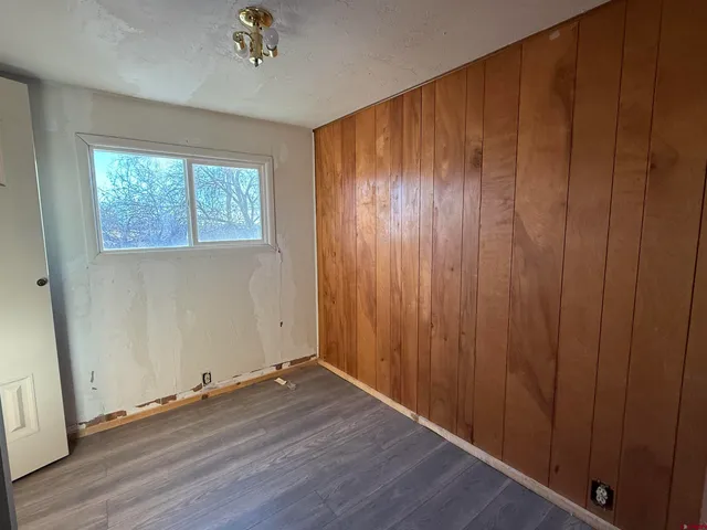 an empty room with wooden floor front door and windows