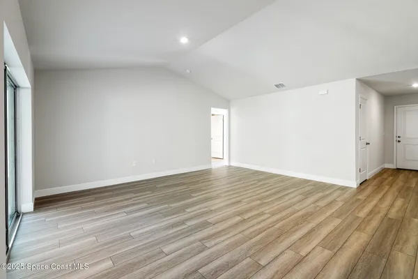a view of large kitchen with kitchen island a sink wooden floor and a refrigerator