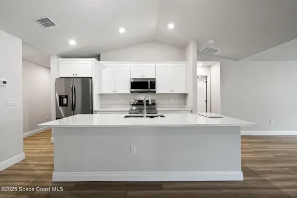 a kitchen with a sink a counter top space stainless steel appliances and cabinets