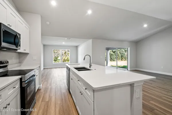 a kitchen with stainless steel appliances a stove a microwave a sink and cabinets