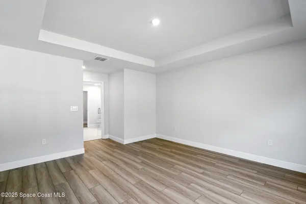 a view of a hallway with wooden floor and a bathroom