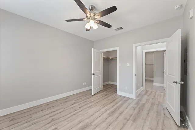 an empty room with wooden floor and a ceiling fan
