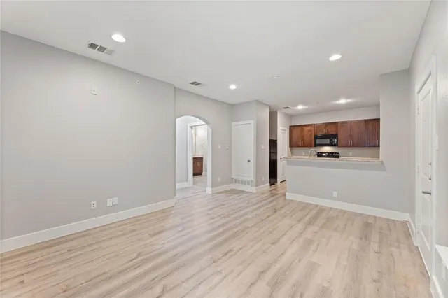 a view of an empty room with kitchen and window