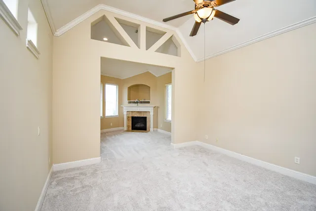 an empty room with fireplace and ceiling fan