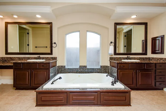 a spacious bathroom with a granite countertop tub double vanity sink and a mirror