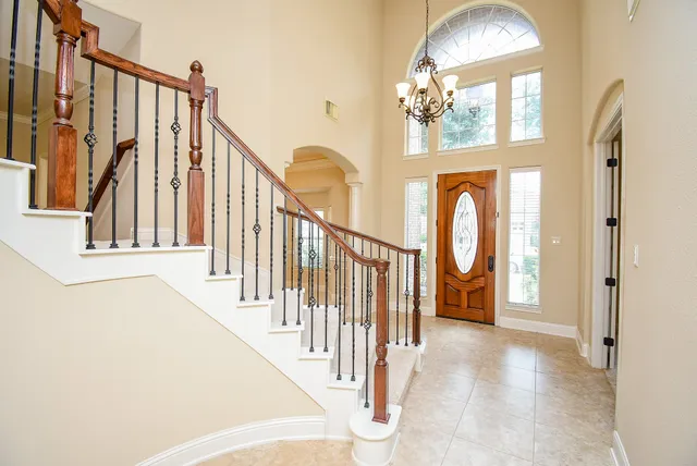a view of staircase with railing and a chandelier