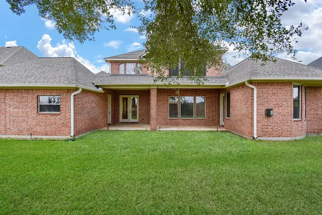 a view of a house with a yard and a large tree