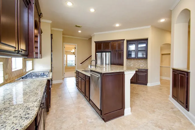 a kitchen with stainless steel appliances granite countertop a refrigerator a stove and a sink