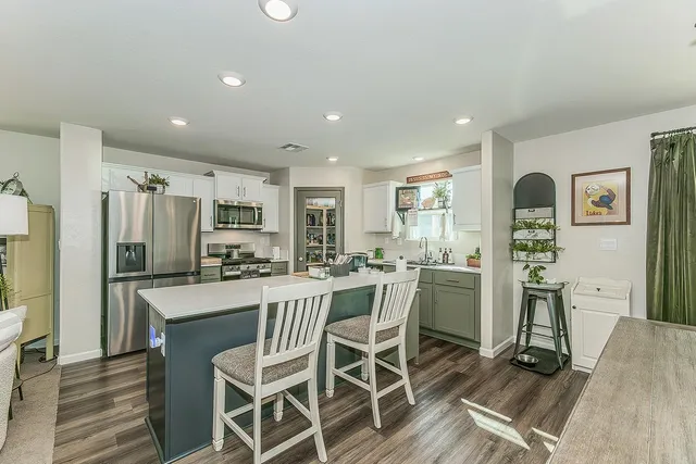 a kitchen with stainless steel appliances a dining table chairs refrigerator and cabinets